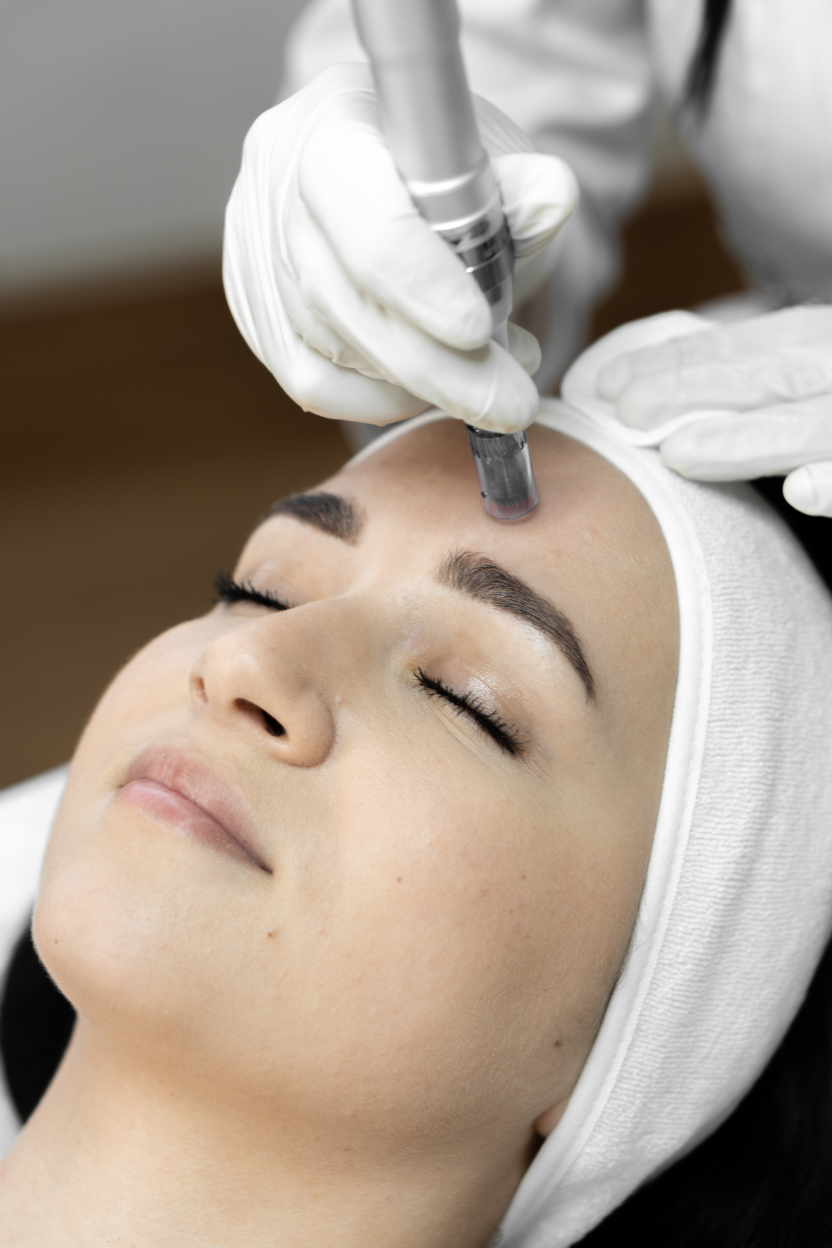 The beautician in the clinic performs fractional facial mesotherapy, introducing useful beauty substances that help improve skin tone and reduce signs of aging. Woman in beauty salon